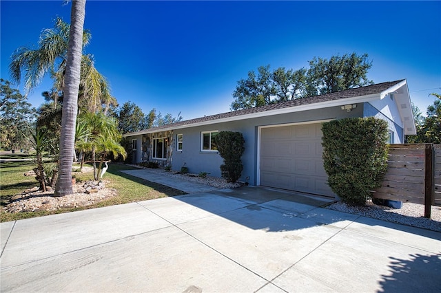 ranch-style home featuring driveway, an attached garage, and stucco siding