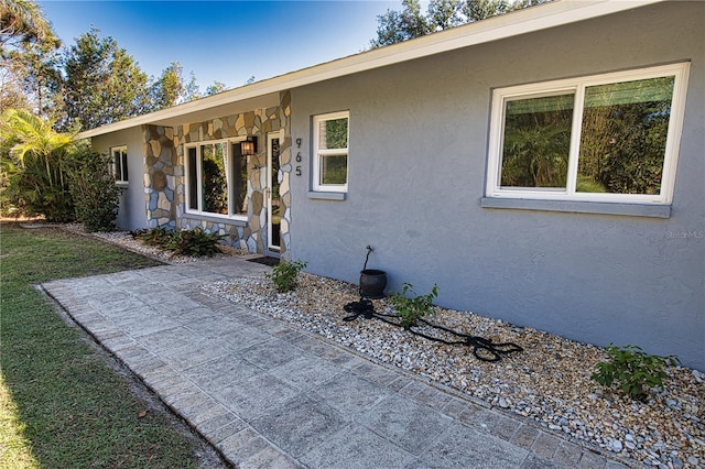 view of exterior entry featuring stone siding and stucco siding