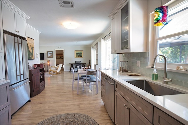 kitchen featuring stainless steel appliances, a sink, visible vents, light countertops, and crown molding