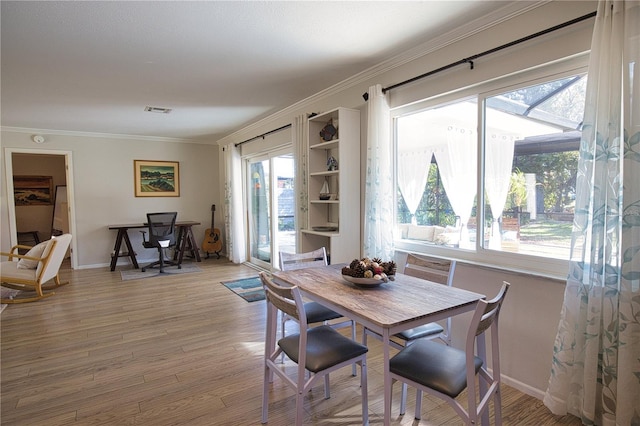 dining area with ornamental molding, plenty of natural light, visible vents, and light wood-style floors