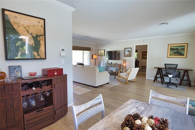 living room with ornamental molding, baseboards, visible vents, and light wood finished floors