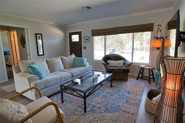 living area with baseboards, crown molding, visible vents, and wood finished floors