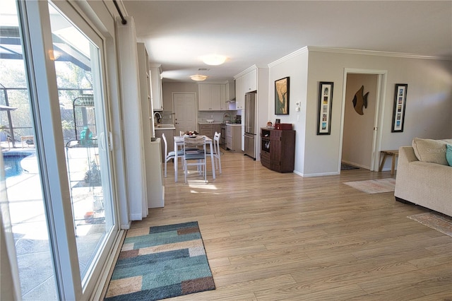 living area with light wood-style floors, baseboards, and ornamental molding