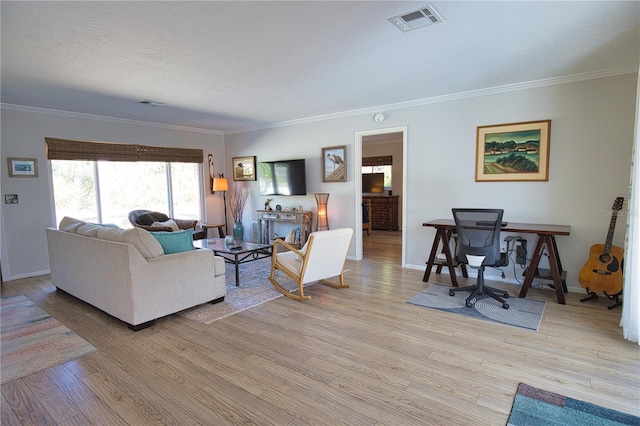 living area with ornamental molding, light wood-style flooring, visible vents, and baseboards