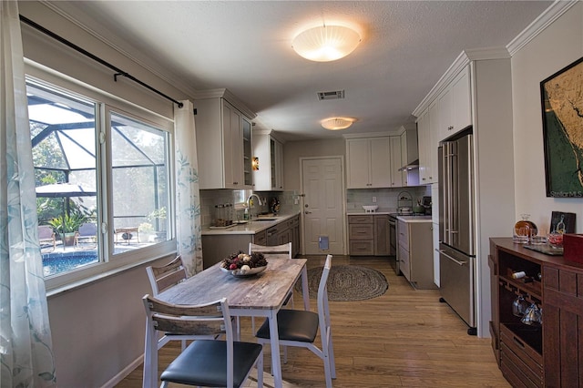 kitchen featuring stainless steel appliances, visible vents, light countertops, backsplash, and light wood finished floors