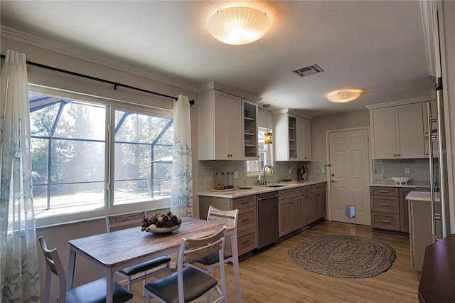 kitchen with wood finished floors, visible vents, light countertops, dishwasher, and glass insert cabinets