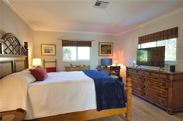 bedroom featuring ornamental molding, wood finished floors, and visible vents