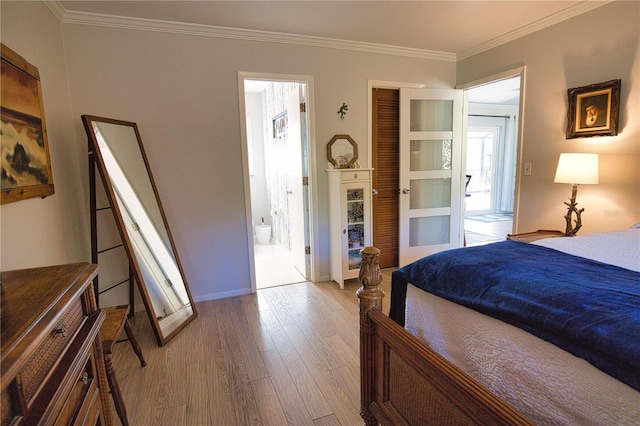 bedroom with baseboards, crown molding, ensuite bath, and wood finished floors