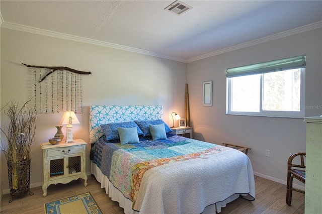 bedroom featuring visible vents, crown molding, and wood finished floors