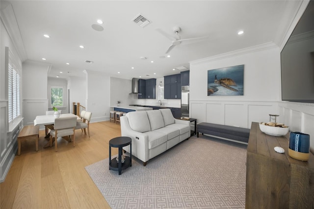 living area with recessed lighting, a decorative wall, visible vents, light wood-type flooring, and crown molding