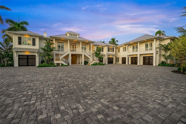 view of front of home with stairs, driveway, an attached garage, and stucco siding