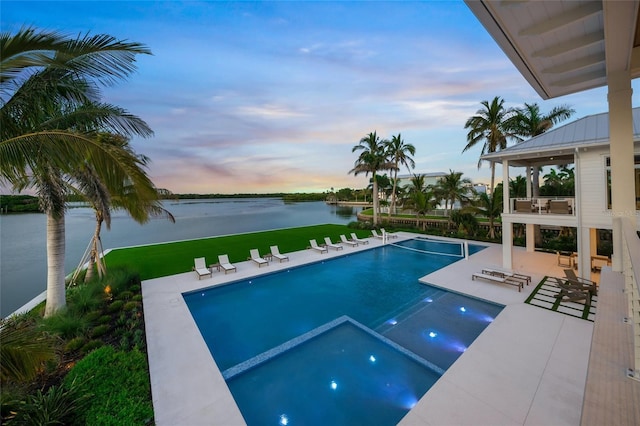 view of pool with a patio area, a water view, and a pool with connected hot tub