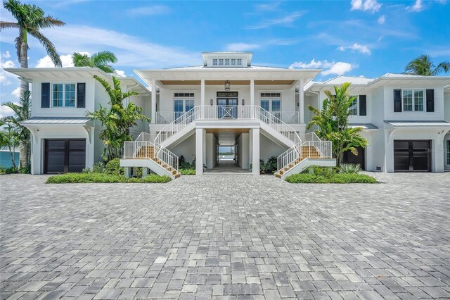 beach home featuring metal roof, covered porch, a garage, decorative driveway, and a standing seam roof