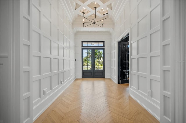 foyer entrance with coffered ceiling, a high ceiling, a decorative wall, and crown molding