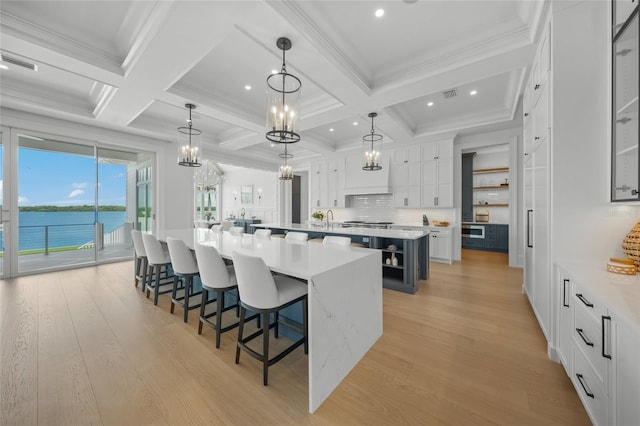 kitchen featuring a large island, visible vents, white cabinetry, light wood-type flooring, and a kitchen breakfast bar