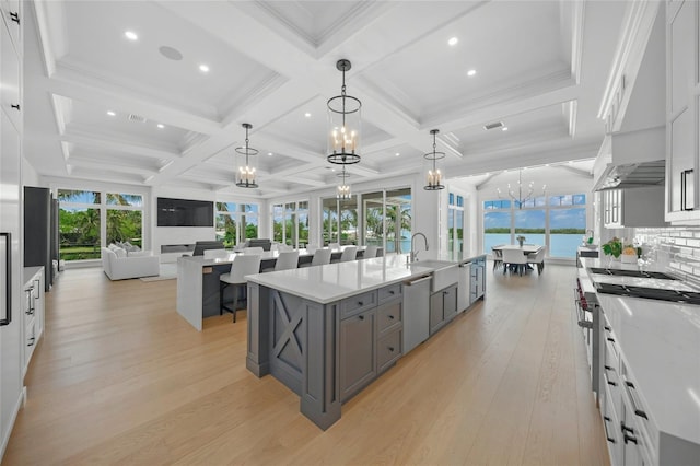 kitchen featuring a large island, open floor plan, stainless steel appliances, gray cabinets, and a notable chandelier