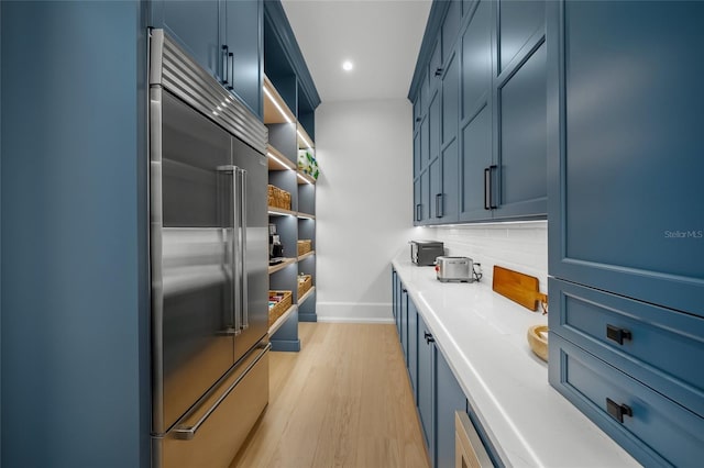 kitchen with built in fridge, open shelves, light countertops, light wood-style floors, and baseboards