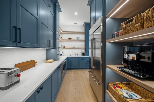 kitchen featuring blue cabinets, light countertops, stainless steel built in fridge, and open shelves