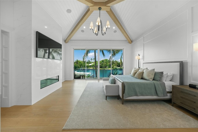 bedroom featuring a premium fireplace, beamed ceiling, access to exterior, an inviting chandelier, and light wood-style floors