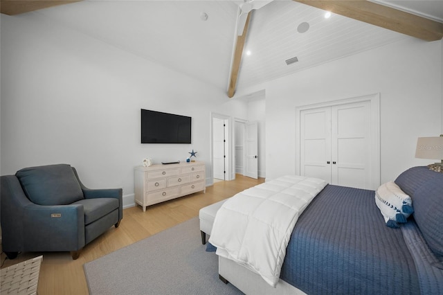 bedroom featuring light wood-type flooring, a closet, visible vents, and beamed ceiling