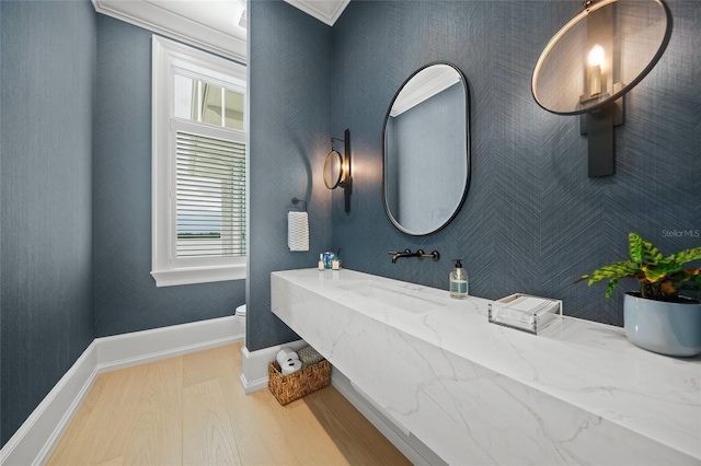 bathroom featuring a healthy amount of sunlight, toilet, a sink, and wood finished floors