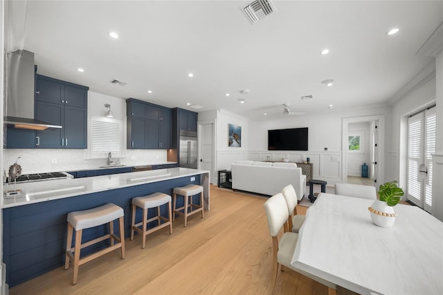 dining area with light wood-type flooring, visible vents, crown molding, and wainscoting