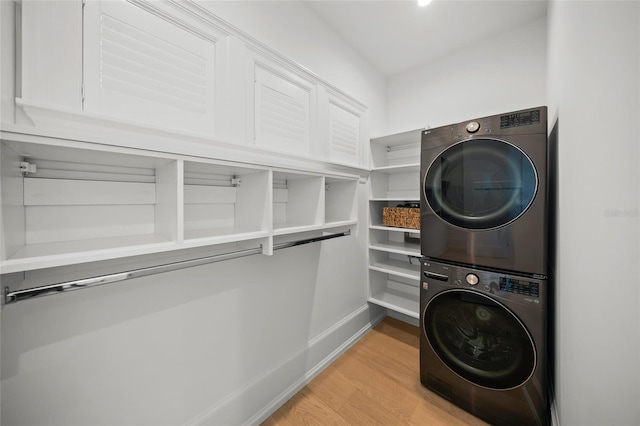 laundry room featuring laundry area, light wood-style flooring, baseboards, and stacked washer / drying machine