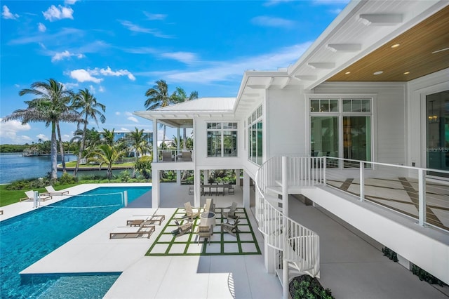 exterior space with stairway, a water view, and an outdoor pool