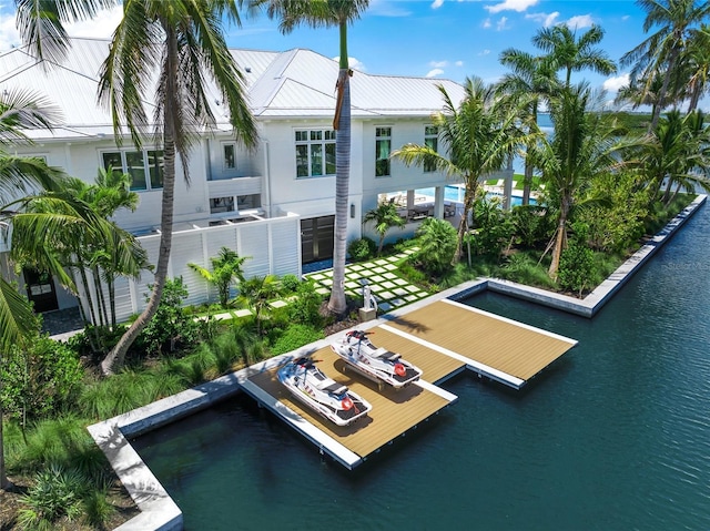 rear view of house featuring a water view, uncovered parking, and metal roof