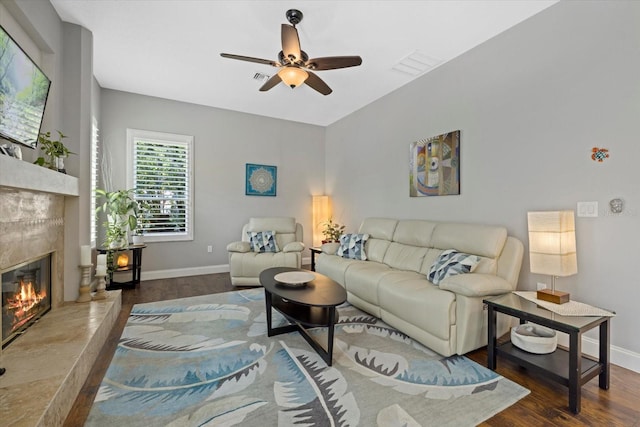 living area with a premium fireplace, wood finished floors, a ceiling fan, visible vents, and baseboards