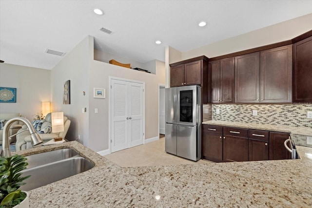 kitchen with refrigerator with glass door, visible vents, backsplash, and a sink