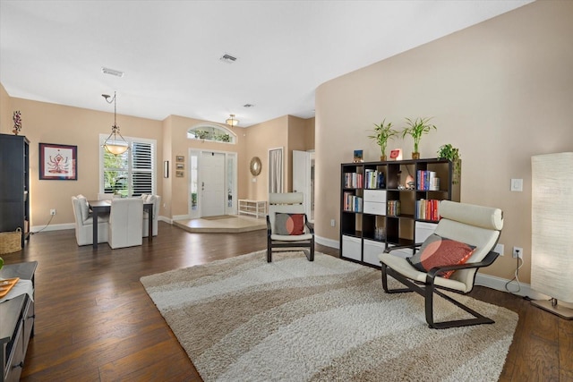 living area featuring dark wood-style flooring, visible vents, and baseboards