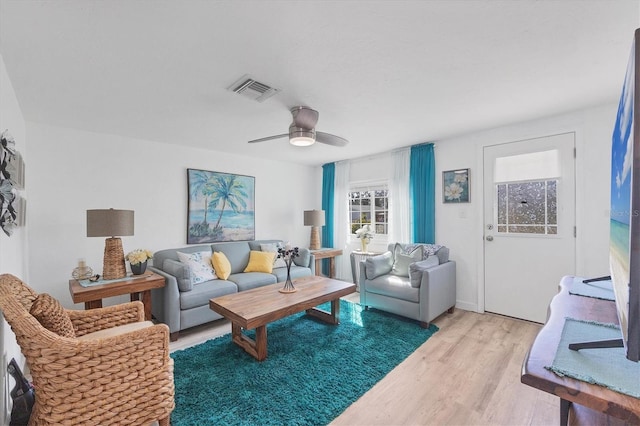 living area with light wood finished floors, visible vents, and a ceiling fan