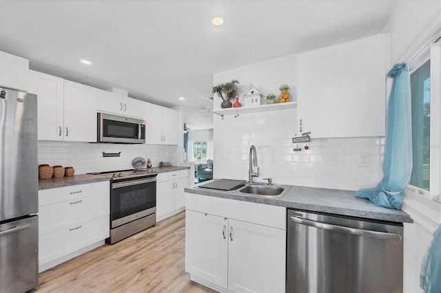 kitchen with stainless steel appliances, a sink, white cabinetry, light wood-type flooring, and open shelves