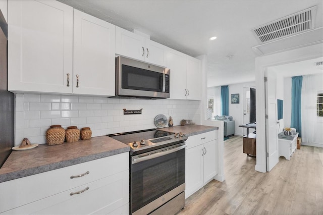 kitchen featuring visible vents, light wood-style flooring, decorative backsplash, appliances with stainless steel finishes, and white cabinets