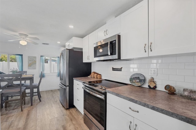 kitchen with white cabinetry, appliances with stainless steel finishes, light wood-type flooring, backsplash, and dark countertops