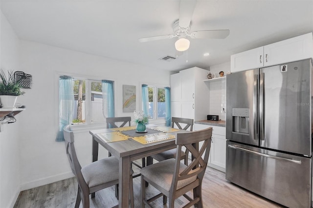 dining room with light wood finished floors, baseboards, visible vents, and a ceiling fan