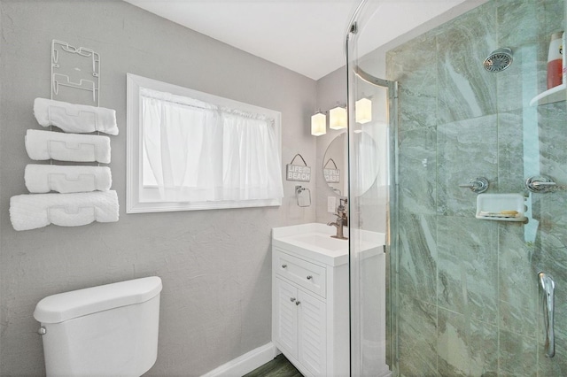 bathroom featuring vanity, a shower stall, toilet, and baseboards