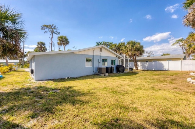 back of house with a lawn, fence, and central AC