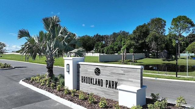 community sign featuring a water view and fence