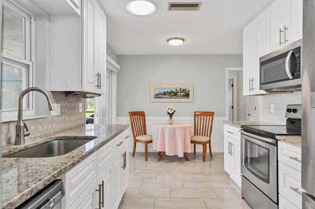 kitchen with visible vents, decorative backsplash, stainless steel appliances, white cabinetry, and a sink