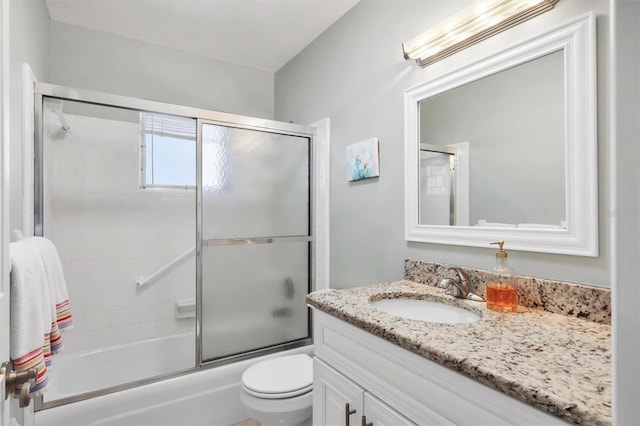 bathroom featuring toilet, enclosed tub / shower combo, and vanity