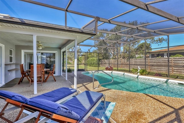 view of pool featuring glass enclosure, a patio area, fence, and a ceiling fan