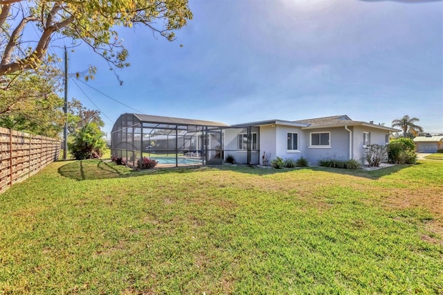 back of house featuring an outdoor pool, glass enclosure, fence, and a lawn