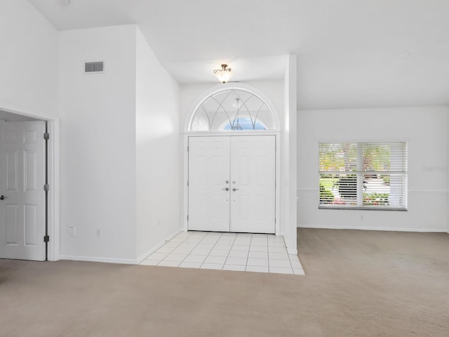 entrance foyer featuring light tile patterned floors, baseboards, visible vents, and light colored carpet