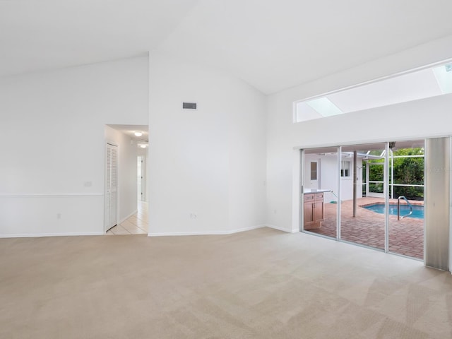 spare room featuring visible vents, high vaulted ceiling, baseboards, and light colored carpet