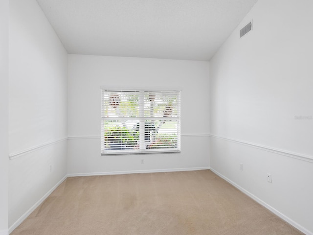 unfurnished room with light colored carpet, visible vents, and baseboards