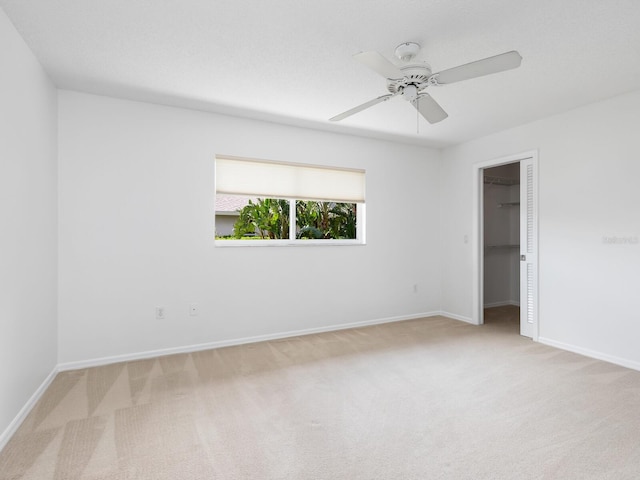 carpeted empty room featuring a ceiling fan and baseboards