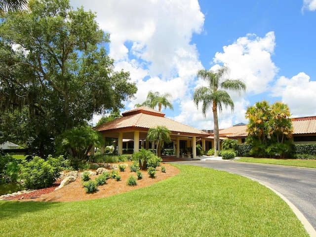 view of front of property featuring driveway, a front yard, and a tile roof