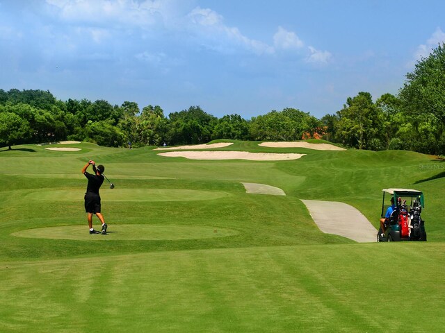 view of home's community featuring view of golf course and a yard